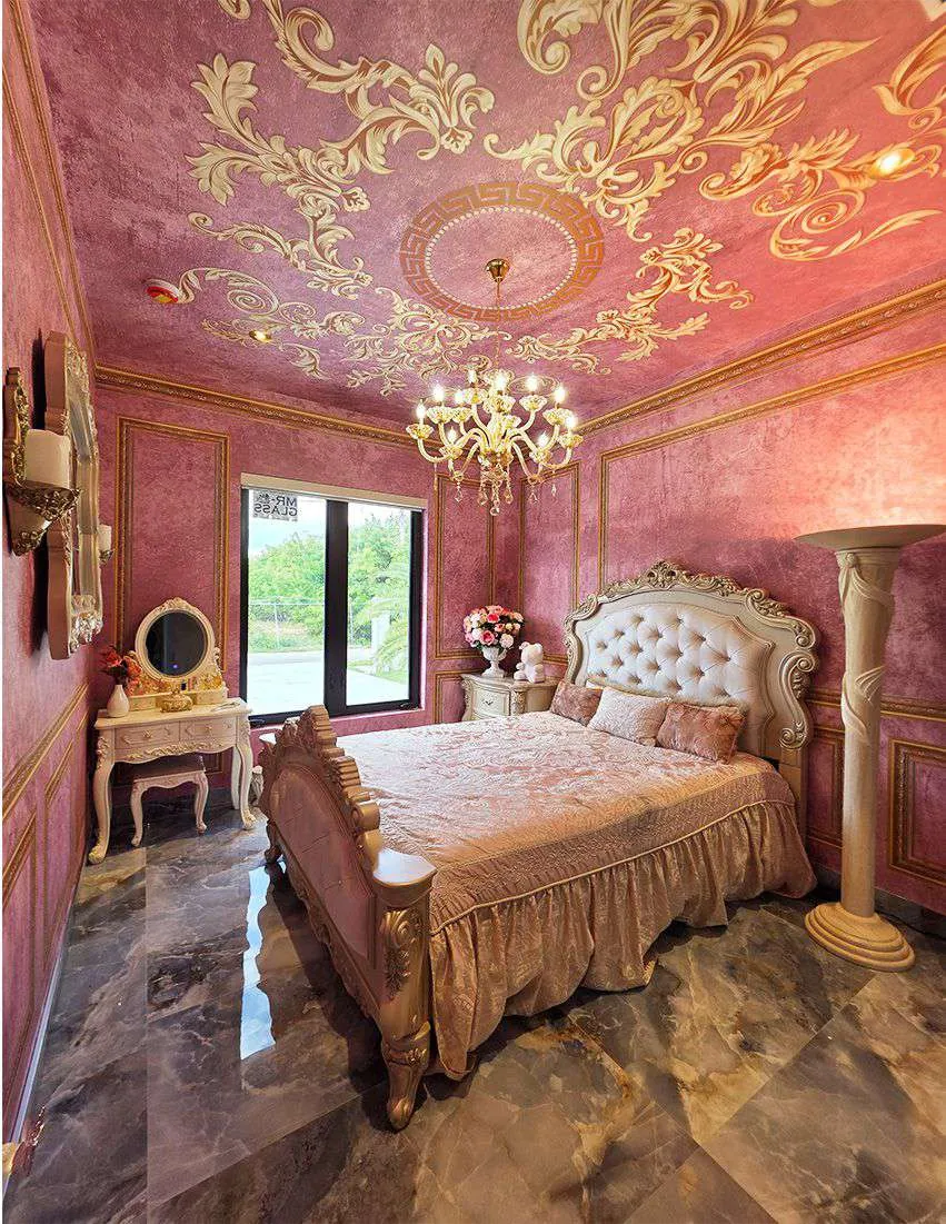 Bedroom in dusty rose with a gold ornamental ceiling and a carved bed