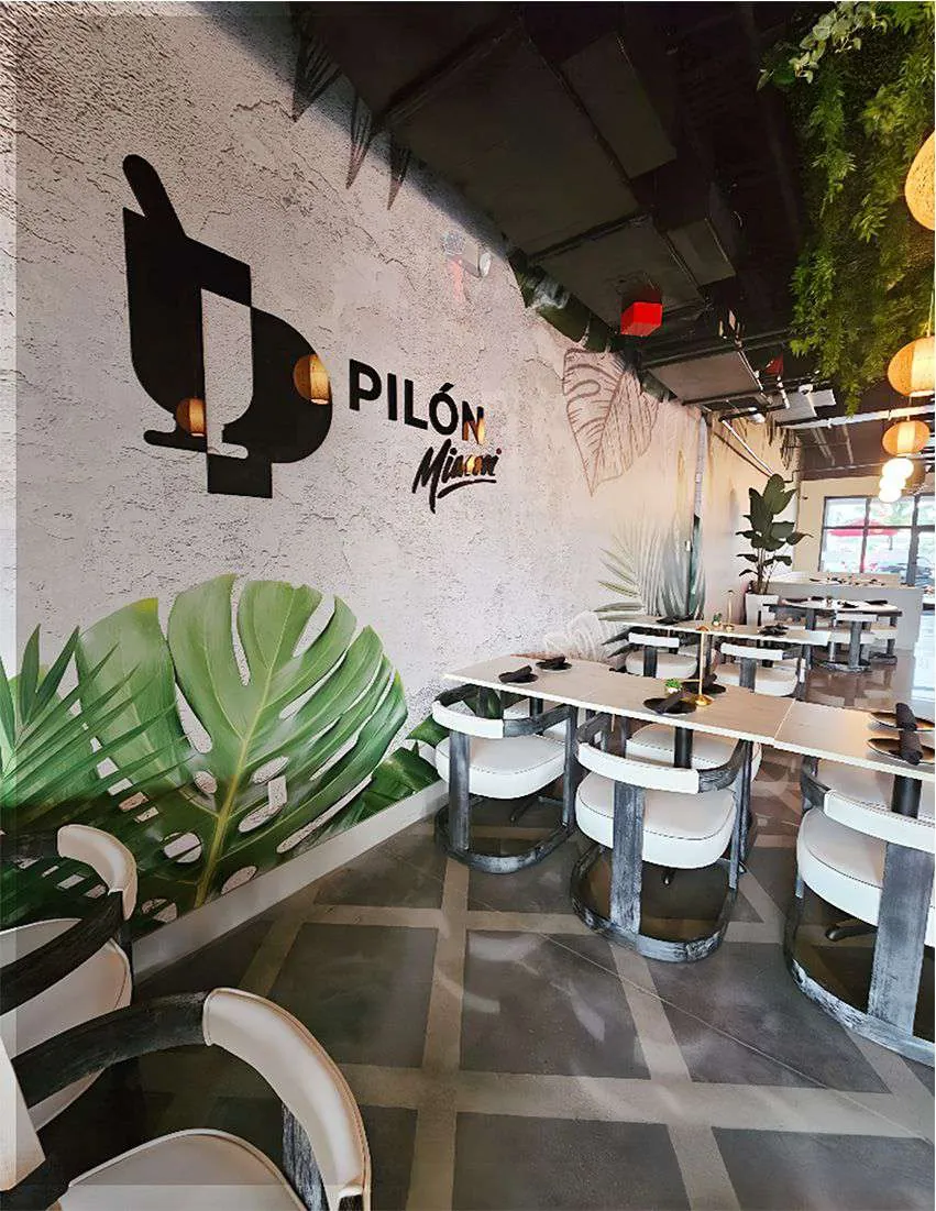 Pilón Miami restaurant with a printed logo wall and a large leaf design